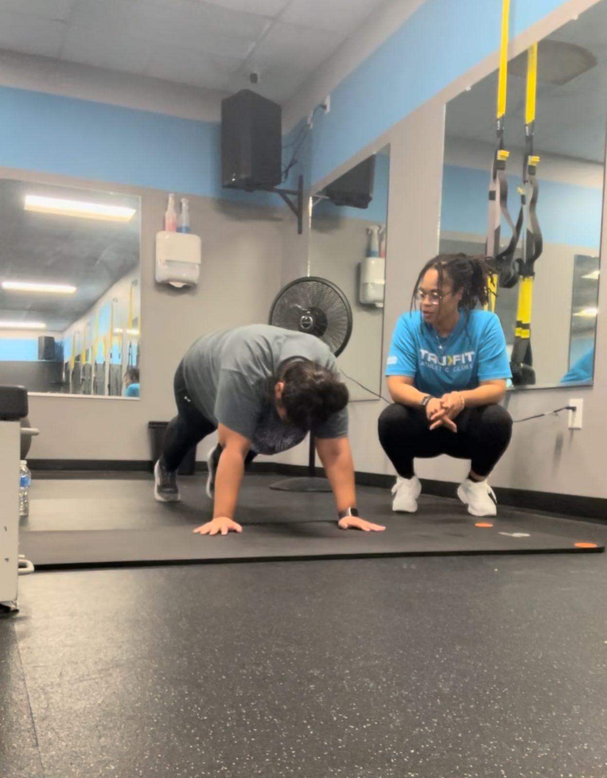 Asya coaching a client through a plank
